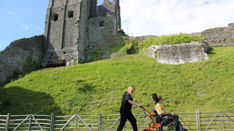 Visitors exploring Corfe Castle in summer using all-terrain electric wheelchair.